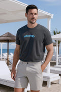 Men's oversized Classic Arch Logo Tee in dark gray with blue logo, paired with light shorts, casual beach style