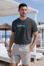 Men's oversized Classic Arch Logo Tee in dark gray with blue logo, paired with light shorts, casual beach style