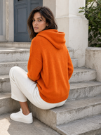 Gebreide hoodie oranje - model zit op buitentrap