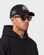 Side print of the black Hustlers Baseball Cap by R3CEIVED on model