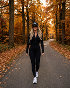 Aspen Ribbed Jumpsuit in black with R3 cap on an autumn forest road