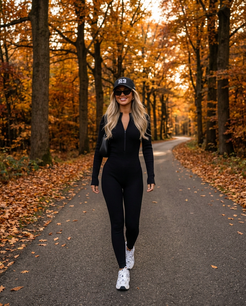 Aspen Ribbed Jumpsuit in black with R3 cap on an autumn forest road