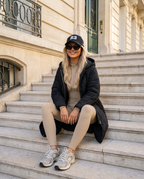 Aspen Ribbed Jumpsuit in beige styled with the Chamonix Quilted Coat in Black, sitting on stone steps